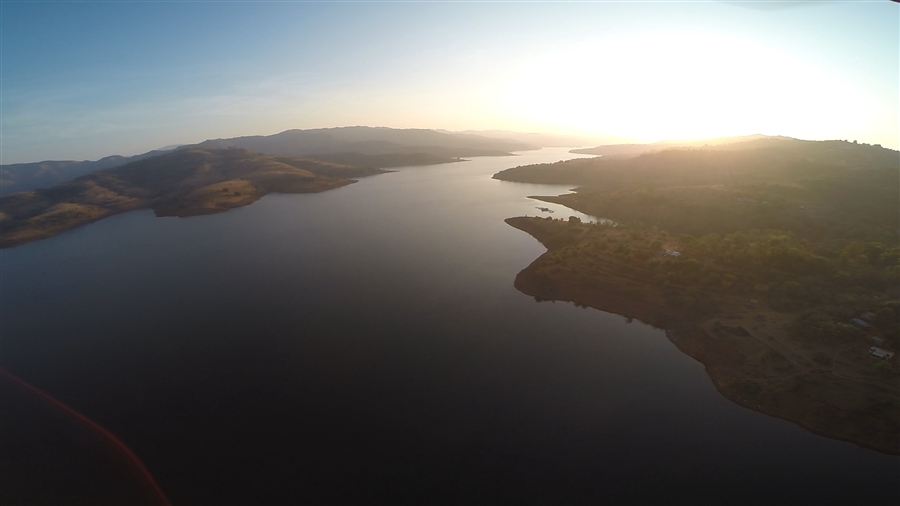 Aerial view of a lake winding through hills at sunset